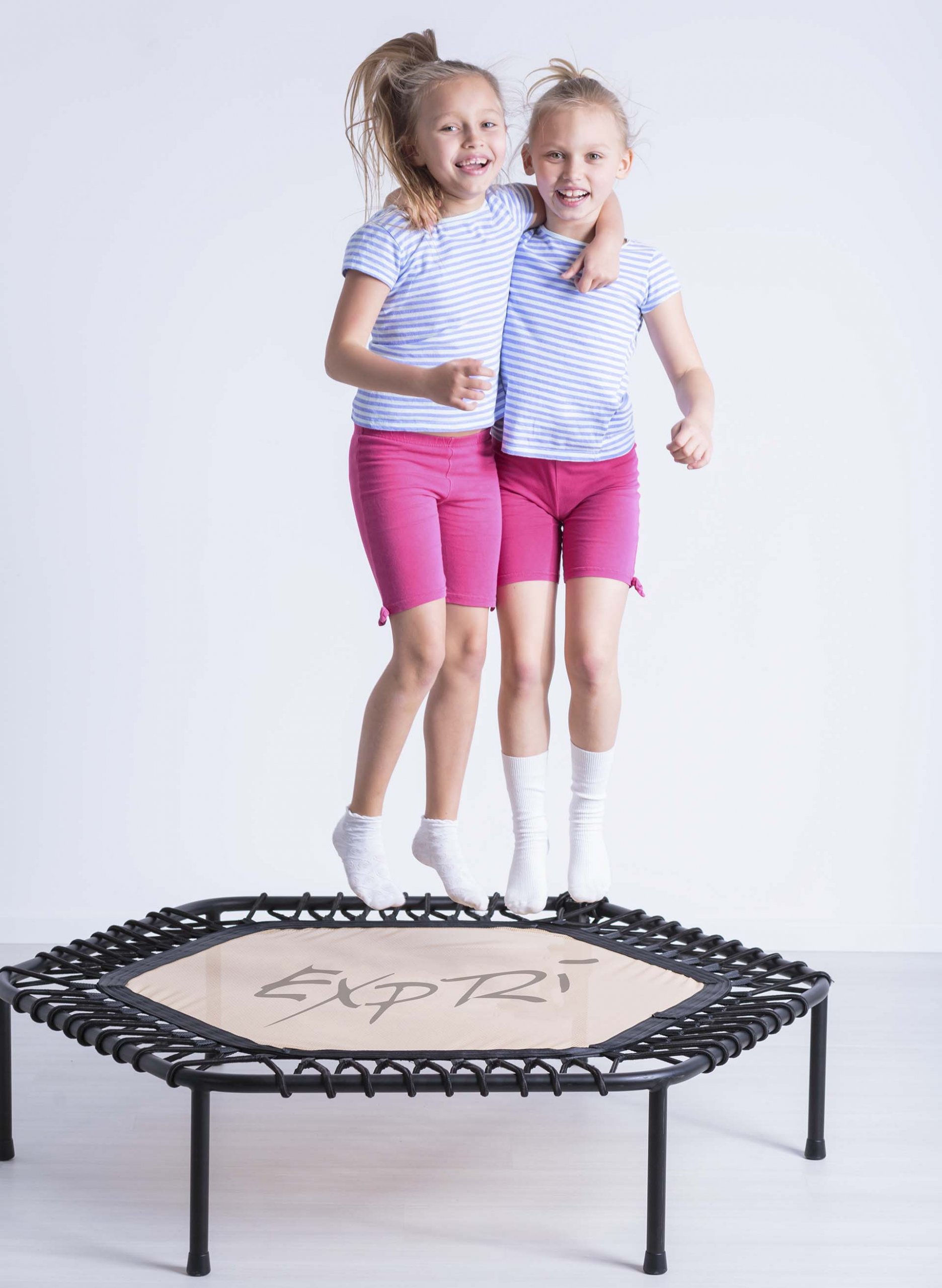 Portrait of smiling embracing girls jumping on trampoline together